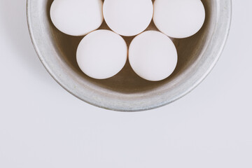 White eggs in metal bowl. Close up, selective focus. Concept scene. 