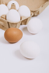 White and brown eggs on bright background and white eggs in brown egg tray. Selective focus. Concept scene. 