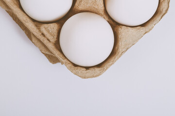 White eggs in brown egg tray on bright background. Selective focus. Concept scene. Top view. 