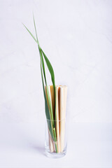 bamboo tubes, drinking straws in a transparent glass on a light background, eco friendly