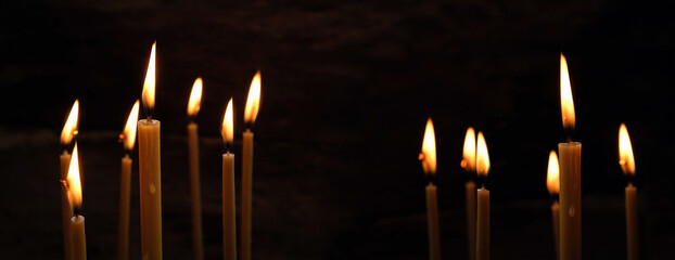 Burning wax candles on abstract black background. candle flame - Symbol of prayer, memory, Lent,...