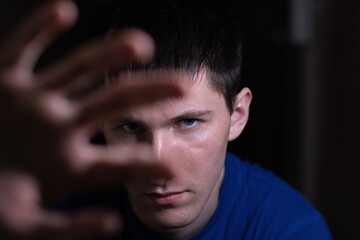 Fototapeta premium Grimly grinning man looks into the camera. he tries to cover himself with his hand