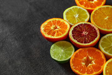 Citrus fruits cut in half, oranges, tangerines, lemons, limes, on dark background, top view, space to copy text