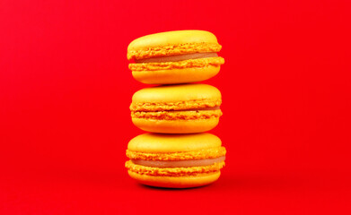 Three yellow macaroons on a red background