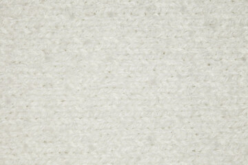 Fabric knitted with threads of white sheep wool yarn close-up, background wallpaper, uniform texture pattern