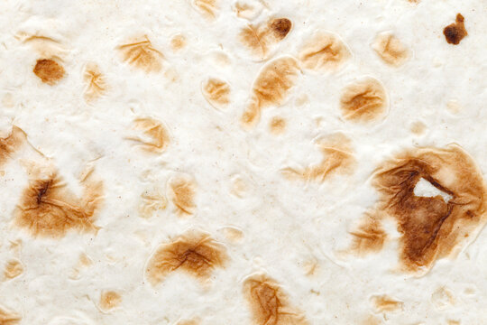 Pita bread tortilla handmade baked in tandoor, baked specks, closeup structure, background wallpaper, uniform texture pattern