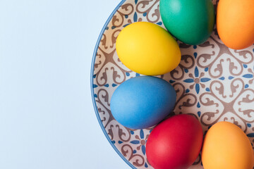 Fototapeta na wymiar Painted eggs. Colorful Easter eggs in the plate. Macro shot, selective focus. Top view.