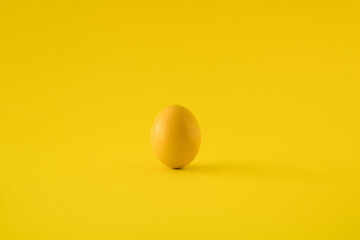 Yellow colored egg on yellow background. Minimal Easter concept.