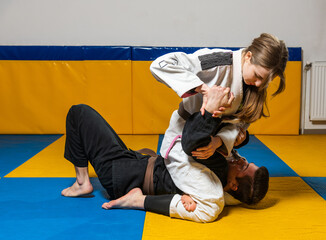 Young girl and boy practice Brazilian jiu jitsu in the gym