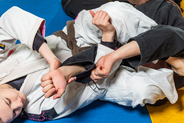 Young girl and boy practice Brazilian jiu jitsu in the gym