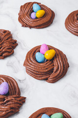 Easter nest cookies. Nest shape cookies with multicolored easter eggs in the center. Easter eggs covered by colorful candy shell.  Baked chocolate nests cookies.