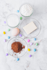 Ingredients for cooking. Eggs, cacao, piece of butter, flour, sugar, colorful candy eggs on table. Ingredients for making dough. Ingredients for baking cookies. Top view.