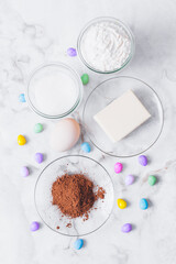 Ingredients for cooking. Eggs, cacao, piece of butter, flour, sugar, colorful candy eggs on table. Ingredients for making dough. Ingredients for baking cookies. Top view.