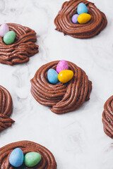 Easter nest cookies. Nest shape cookies with multicolored easter eggs in the center. Easter eggs covered by colorful candy shell.  Baked chocolate nests cookies.