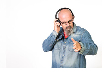 hombre de mediana edad calvo con perilla y gafas escuchando musica con auriculares en el movil...