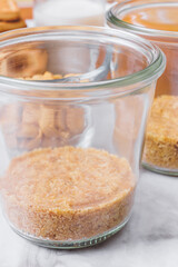 Ingredients for cooking. Grinded cookies in glass jar on table. Selective focus. Macro shot.