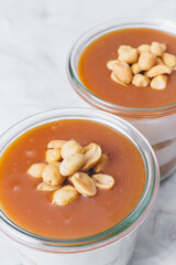 Cheesecake in a jar. Layers of grinded cookies, caramel, peanuts and  cream cheese. Covered in...