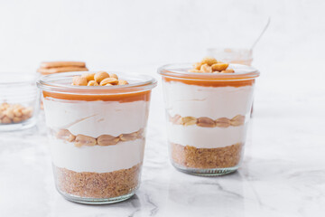 Cheesecake in a jar. Layers of grinded cookies, caramel, peanuts and  cream cheese. Covered in...