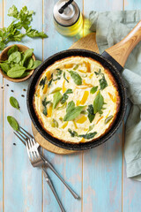 Healthy frittata or stuffed omelette in pan on rustic wooden background. Italian omelette with organic spinach and bell pepper. View from above.