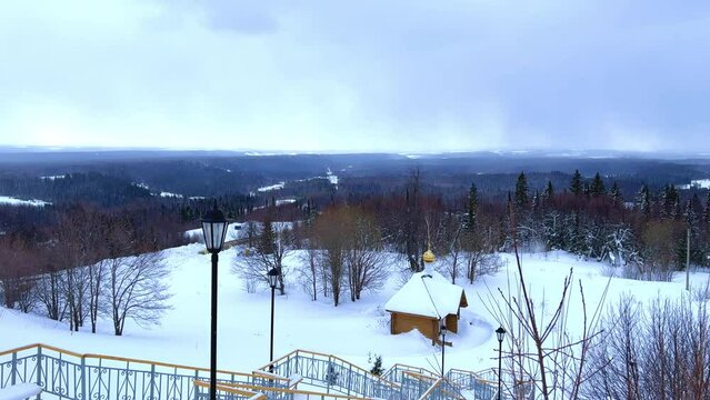 View of the chapel near the Belogorsky St. Nicholas Orthodox Missionary Monastery. Winter forest. The temple on the hill in winter. Russia, Perm Krai, Belaya Gora. 4K