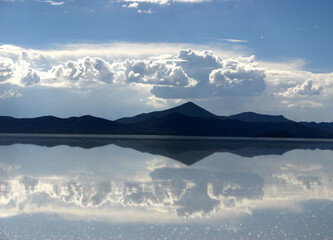 beautiful landscape image of the sky, clouds and mountains mirrored in the layer of water on the ground