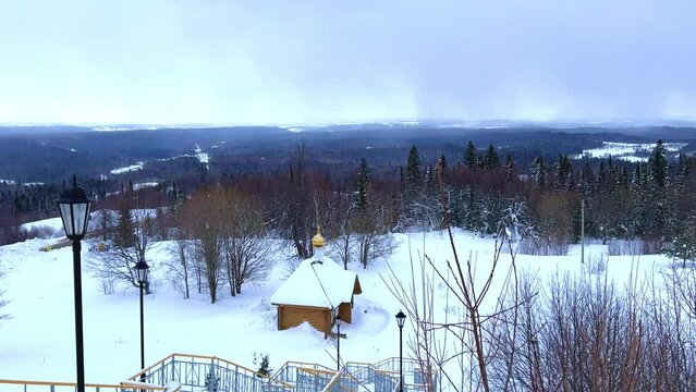 View of the chapel near the Belogorsky St. Nicholas Orthodox Missionary Monastery. Winter forest. The temple on the hill in winter. Russia, Perm Krai, Belaya Gora. 4K