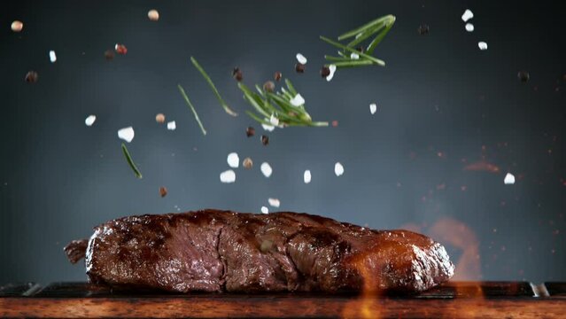 Flying piece of grilled beef steak with falling spice . Filmed on high speed cinema camera, 1000 fps. Fire on foreground.