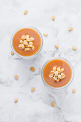 Glass jars with caramel, decorated with salty peanuts on table. Top view.