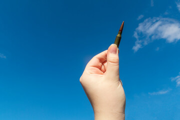 Rifle cartridge in hand against the blue sky. Close-up