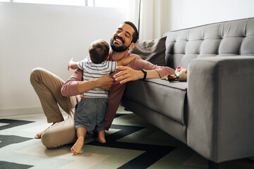 Happy father hugging little son at home. Happy Brazilian father embracing son - obrazy, fototapety, plakaty