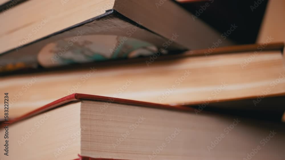 Poster close-up of a stack of colorful old hardcover books in the rays of sunlight. camera movement from bo