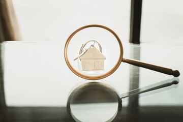 Magnifying glass for looking at house key model, house selection, real estate concept.