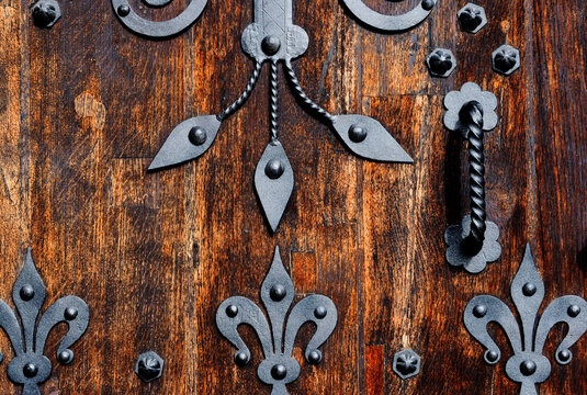 vintage weathered rustic oak door decorative black wrought iron mounting. textures and patterns. peep window with forged iron bar grille. ancient architecture concept. old grunge look. macro view. 