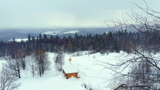 View of the chapel near the Belogorsky St. Nicholas Orthodox Missionary Monastery. Winter forest. The temple on the hill in winter. Russia, Perm Krai, Belaya Gora. 4K