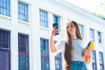 girl podroktos student communicates via video call using a smartphone, outside