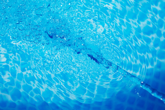 Filling a pool with fresh water. Water movement and focus on air bubbles, blue clear water background with copy space