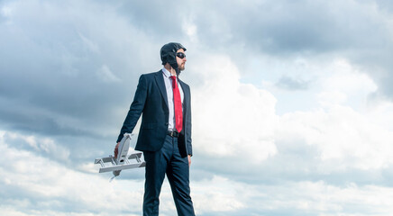 businessman in suit and pilot hat launch plane toy on sky background. inspiration