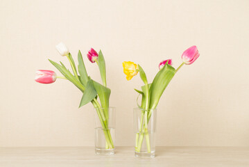 Tulip flowers in vases on wooden table