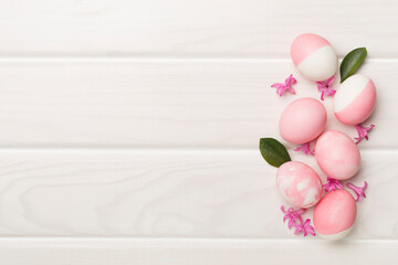 Pink Easter eggs with decor on wooden background, top view