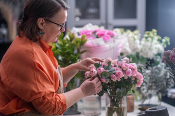 The skilled female florist artfully prepares a gorgeous bouquet of diverse spring flowers, working meticulously at her flower store