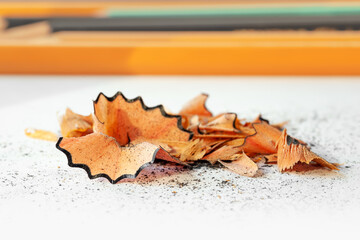 Pencil shavings. Wooden pencil shavings on the background of pencils. Rubbish from sharpener