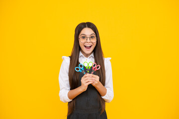 Excited amazed teenage girl with scissors, isolated on yellow background. Child creativity, arts and crafts.