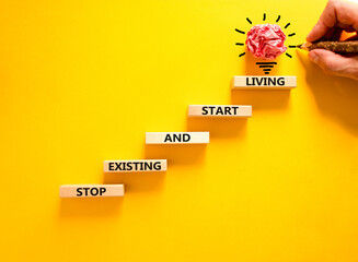Stop existing start living symbol. Concept words Stop existing and start living on wooden blocks....