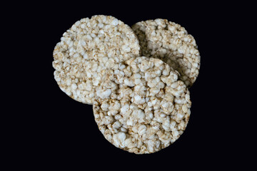 Three round rice crackers on a black background close-up. Crispy rice diet product for a healthy lifestyle. Top view puffed rice cakes on a black isolated background