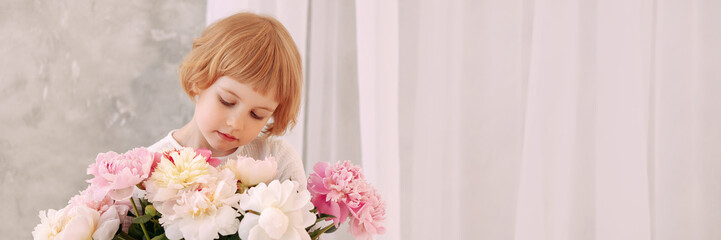 Fototapeta premium Child Blond 6-7 years old in a white dress holds a large bouquet of pale pink flowers in her hand. Concept of congratulations on March 8, Womens Day. Banner for website header design with copy space.