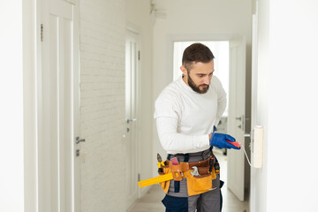 Close-up of person painter holding roller covered in blue paint. Professional worker wearing protective uniform and gloves. Copy space in right side. Renovation concept.