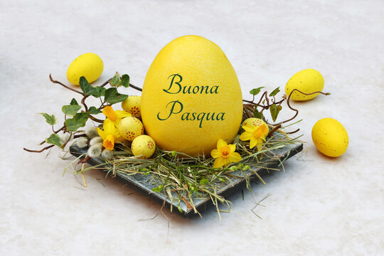 Cartolina d'auguri di buona Pasqua: nido di Pasqua con uova di Pasqua gialle e un uovo di Pasqua con lettere.