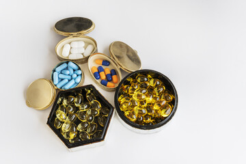 Pills of all kinds in small metal and plastic containers on a plain white background