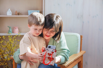 A child takes a photo on a smartphone with his mother, Mother's Day
