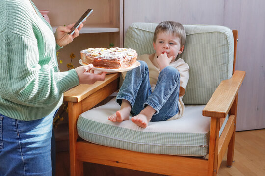 Mother gives her son a cake and takes a picture on the phone